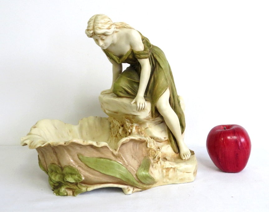 Art Nouveau Royal Dux Porcelain of a Woman Bathing at the Water.: This item is a Royal Dux Bohemia Art Nouveau porcelain centerpiece featuring a young maiden leaning over a stylized shell or pond, perhaps to see herself? Wash her face? dimensions of 11" wide by 11"