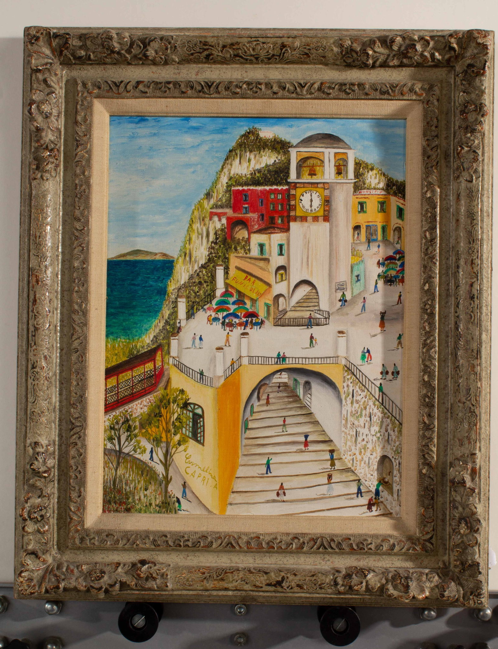 Carmelina A. Capri Oil Painting on Canvas: Ornate framed oil painting on canvas with fabric wrapped mat featuring a clock towering front of hillside, a patio full of people in front of Funicular bar. Signed. Slight ware to frame.