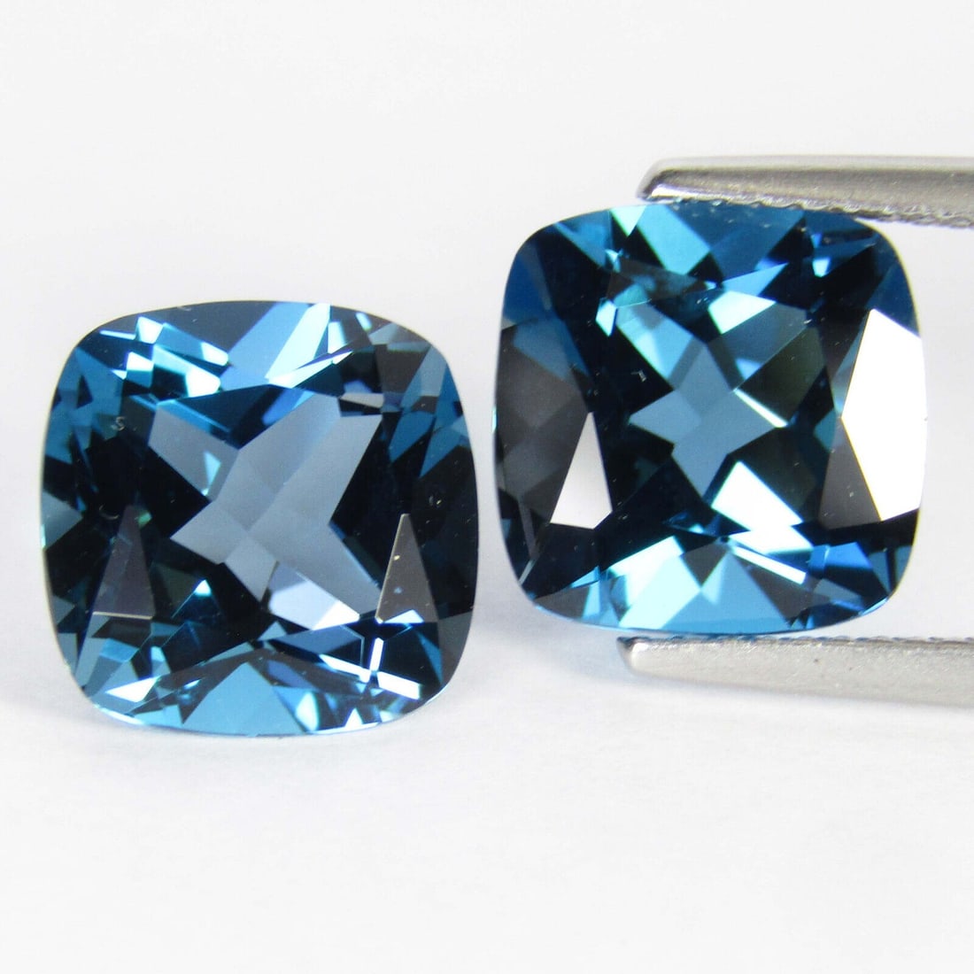 Natural London Blue Topaz 14x14 MM Cushion Cut Gemstone Pair: Natural London Blue Topaz 14x14 MM Cushion Cut Gemstone Pair Gemstone : London Blue Topaz Stone Shape : Cushion Stone Cutting Type : Faceted Cut Stone Weight : 26.90 Carats Stone Measurement :