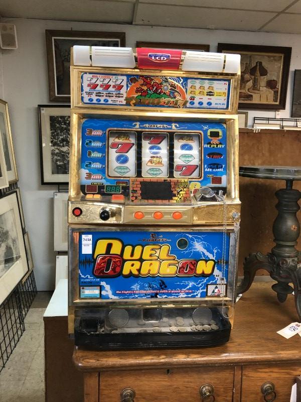 DUEL DRAGON SLOT MACHINE W/TOKENS, WAS OPERATING IN THE: DUEL DRAGON SLOT MACHINE W/TOKENS, WAS OPERATING IN THE GAME ROOM, REMANUFACTURED BY GRANDVIEW PRODUCTS, OVERALL GOOD CONDITION, MEASURES 32" H X 19" W X 14" DEEP
