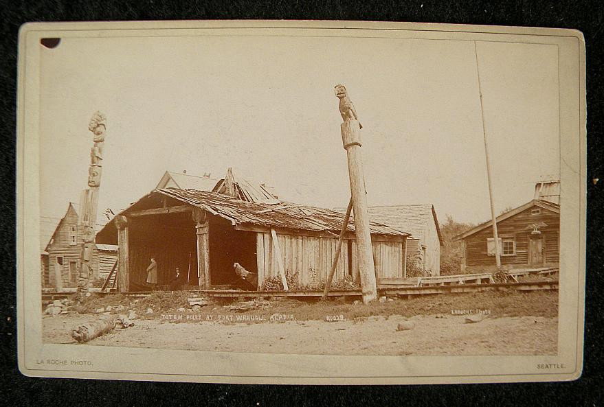 FRANK LA ROCHE ALASKA CABINET PHOTO TOTEM POLES : FRANK LA ROCHE ALASKA CABINET PHOTO TOTEM POLES AT FORT WRANGLE, ALASKA. MEASURES 8" X 5". SHOWS 2 LARGE TOTEM POLES, 2 PEOPLE IN BUILDING, AND CARVED EAGLE OVER DOORWAY ON RIGHT SIDE BUILDING.