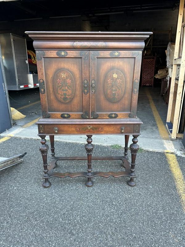 1920's walnut cabinet with floral painted motif, adjustable shelf on top, structurally sound. A: 1920's walnut cabinet with floral painted motif, adjustable shelf on top, structurally sound. A little veneer strip off on very top back edge, measures 56.5" high x 38" wide x 17" deepâ€¦..from lo