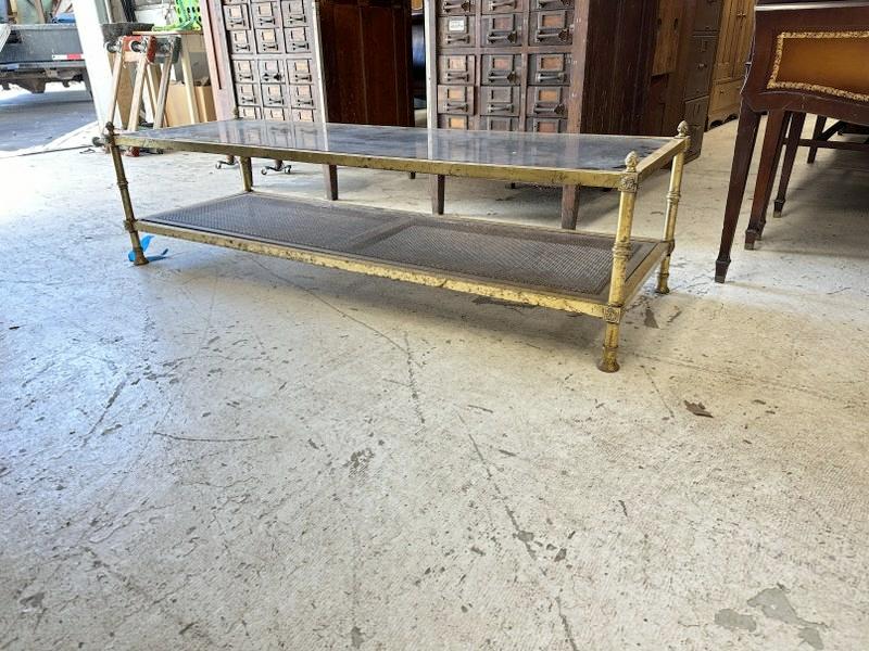 1970's brass plated metal coffee table with smoked glass top, caned bottom shelf & pineapple: 1970's brass plated metal coffee table with smoked glass top, caned bottom shelf & pineapple finials. Brass has wear to finish, measures 60" long x 20" wide x 16" high.