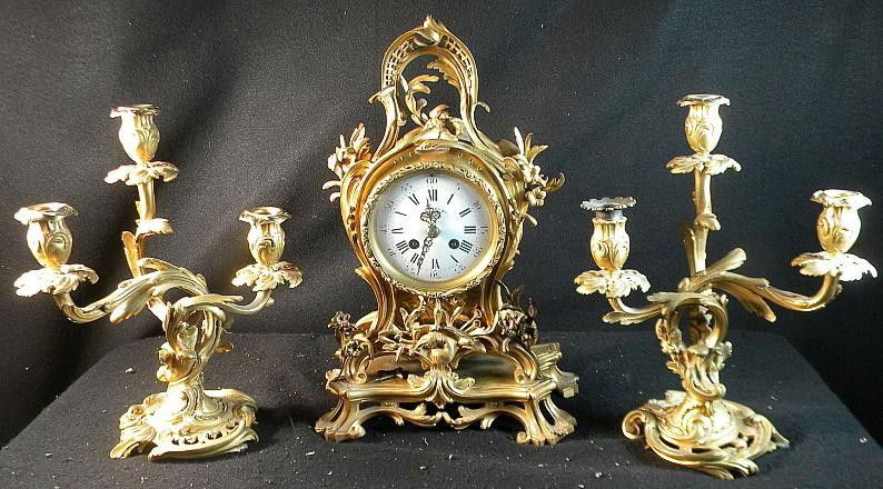 Tiffany & Co. 3 Pc. Bronze Clock Set Made In France: Tiffany & Co. 3 Pc. Bronze Clock Set Made In France, with 2 candelabras. One candelabra has a replacement candle insert, and small piece of flower is off on the clock base, the piece is there, but has