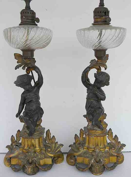 Pair Bronze CHERUB Decorative Oil Lamps: Pair Bronze CHERUB Decorative Oil Lamps, converted to electric. Nice patina, figures are hollow bronze, lamps measure 35" to top of harps, to top of glass is 19". One cherub joint is separated from wa