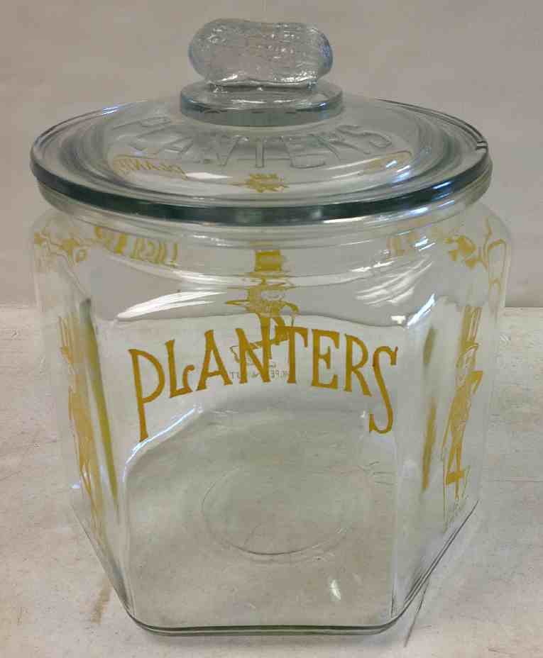 Old PLANTERS PEANUT Jar with Figural Peanut on Lid: Old PLANTERS PEANUT Jar with Figural Peanut on Lid, has one small chip on outside edge of lid. Nice graphics, with no wear, measures 9" high.