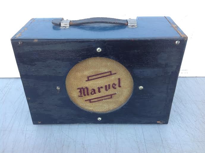 EARLY MARVEL SMALL GUITAR AMPLIFIER IN ORIGINAL BLUE: EARLY MARVEL SMALL GUITAR AMPLIFIER IN ORIGINAL BLUE PAINT, PAINT HAS WEAR AS PICTURED. MEASURES 11 1/2" ACROSS, 8" HIGH AND 5 1/2" DEEP. FRONT PANEL HAS BLACK PAINT. STRAP HANDLE IS BROKEN AT ONE END