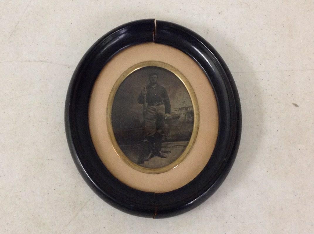 CIVIL WAR TINTYPE OF EDWIN M. PETTENGILL, MA 44TH: CIVIL WAR TINTYPE OF EDWIN M. PETTENGILL, MA 44TH INFANTRY, CO. E, ID ON BACK OF FRAME, POSED WITH MUSKET BEFORE CAMP SCENE BACKDROP, AS PICTURED