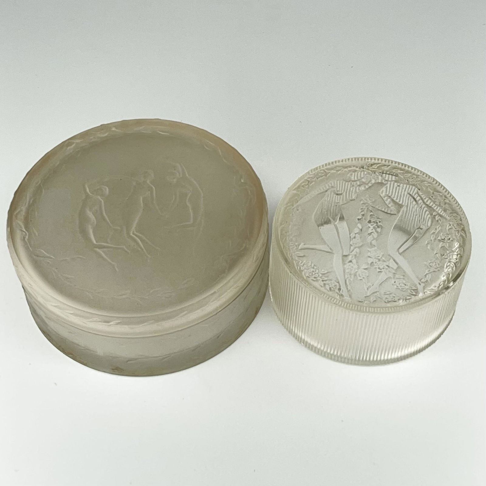 Two Lalique Powder Boxes, Trois Danseurs, Two Art Deco Nudes: Lot of two. â€¨â€¨1) R. Lalique frosted glass circular covered box, â€œTrois Danseurs”, the base marked â€œR. Lalique - France”. 1 1/2” high x 3 3/4” diameter.