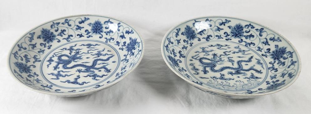 Pair of Blue & White Porcelain Dragon Plates: Set of 2 blue and white Chinese porcelain plates. A five claw dragon is shown chasing a flaming ball, a popular Chinese motif symbolizing the search for fortune. The plates each measure approximately 