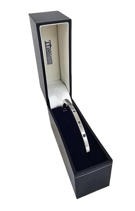 Tanzanite International Flush Set Bangle Bracelet: Tanzanite International brand bangle bracelet with embedded stones, believed to be tanzanite or aquamarine (too small to test). Stones have a bluish color. Measures 2 3/4" wide when clasped. The brace