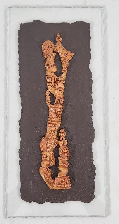 Marquesan Wood Carving on Paper Relief on Glass: A Marquesan folk art wood carving with intricate detail, adhered to a brown paper relief backing, which is adhered to a piece of stylized glass. Measures 5 7/8" W x 12 1/2" H x 5/8" D. Weighs 1.25 lbs