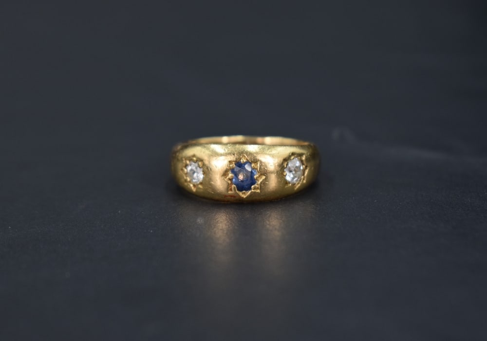 A Victorian three stone 18ct gold band ring having a central sapphire flanked by two diamonds, (1 of 3)