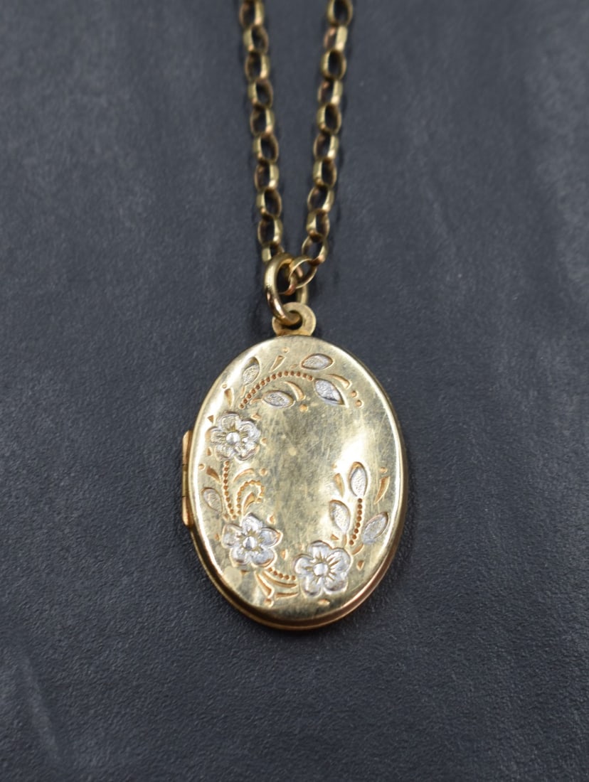 A yellow metal oval locket having a decorative floral design engraving on a 9ct gold rolo chain, 7.: A yellow metal oval locket having a decorative floral design engraving on a 9ct gold rolo chain, 7.1g gross