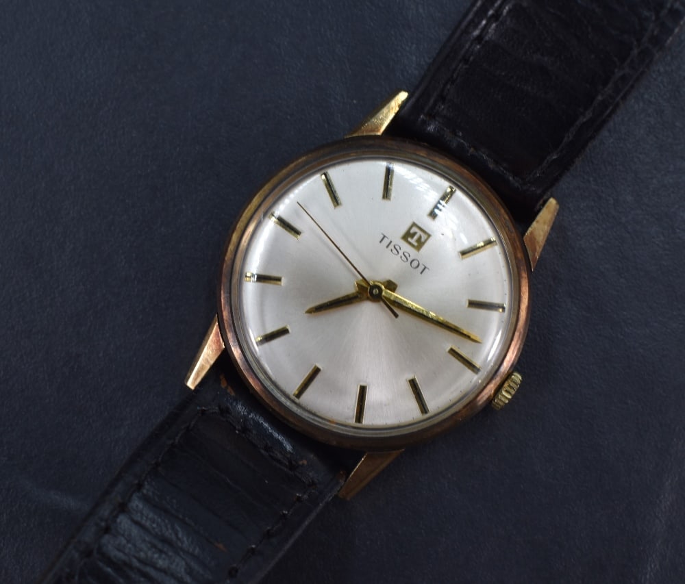 A gent's Tissot 9ct gold manual wristwatch having a baton numeral dial on silvered face in a plain: A gent's Tissot 9ct gold manual wristwatch having a baton numeral dial on silvered face in a plain gold case and black leather strap, 34mm case, watch working when wound but we do not test for functio