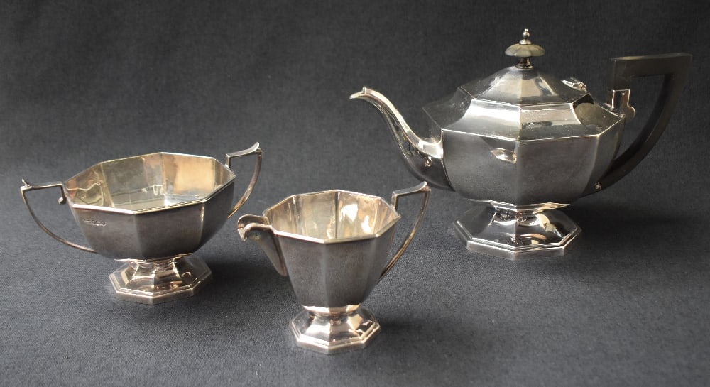 A George VI silver three piece tea set, comprising a tea pot, cream and sugar, having tapered: A George VI silver three piece tea set, comprising a tea pot, cream and sugar, having tapered geometric octagonal bodies, with angular handles raised on octagonal moulded step feet, marks for Sheffiel