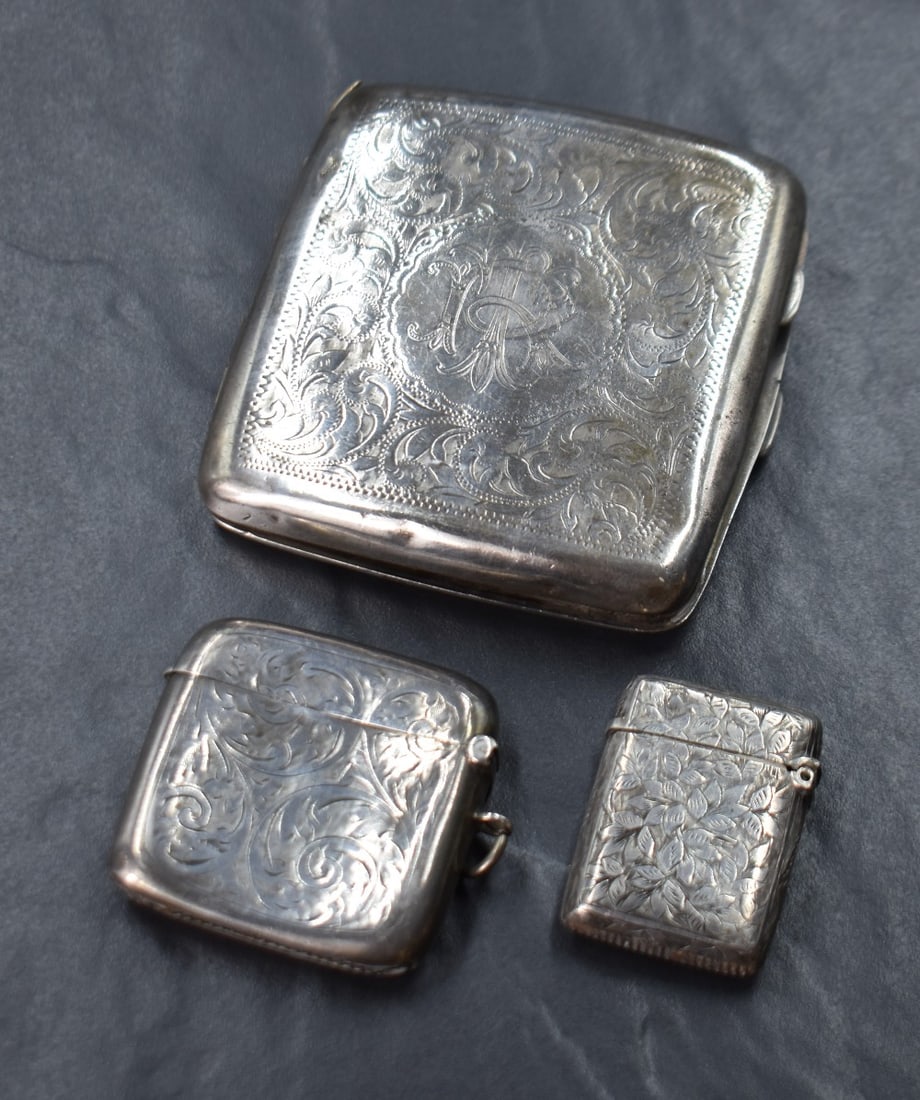 A George V silver cigarette case of hinged square form, having engraved floral scroll decoration: A George V silver cigarette case of hinged square form, having engraved floral scroll decoration with a central circular cartouche engraved with 'TR' monogram, marks for Birmingham 1919, maker Henry H