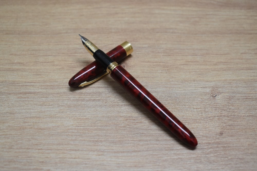 A Sheaffer Crest converter fill fountain pen in red and black with gold plated band to cap having (1 of 3)