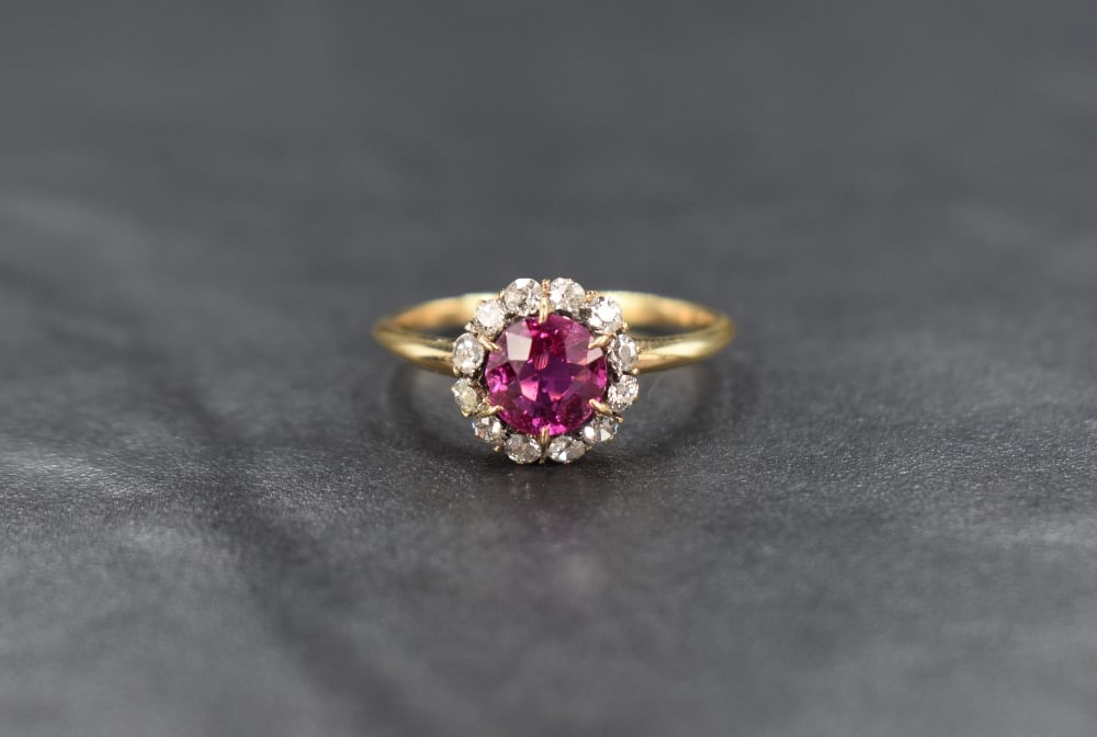 A yellow metal pink sapphire and diamond cluster ring, the round cut pink sapphire measuring (1 of 2)