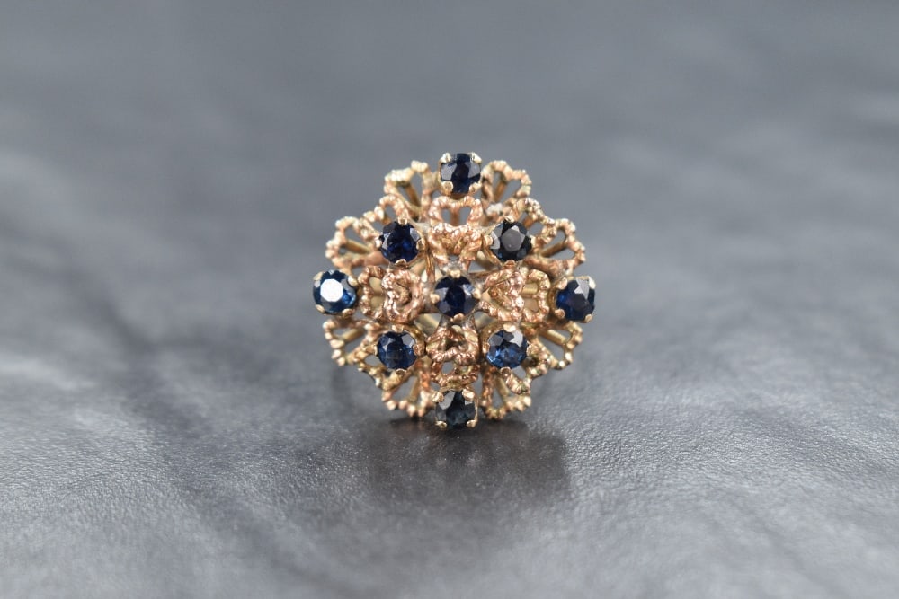 A modern 18ct gold sapphire ring, the nine round cut sapphires set in a contemporary multi-level: A modern 18ct gold sapphire ring, the nine round cut sapphires set in a contemporary multi-level branched design of twisted heart motifs, ring size J, 5.1g