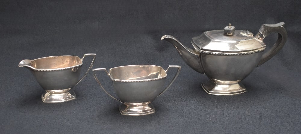 An Elizabeth II silver three-piece tea set comprising a tea pot, sugar and cream, all of rectangular: An Elizabeth II silver three-piece tea set comprising a tea pot, sugar and cream, all of rectangular form, having gadrooned rims and angular handles, raised on rectangular step moulded feet, marks for