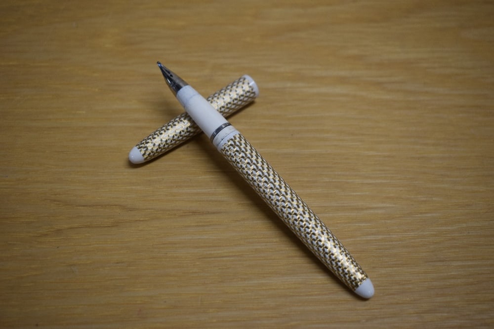 A Lady Sheaffer Skripsert 5 cartridge fill fountain pen in gold and white having Sheaffer: A Lady Sheaffer Skripsert 5 cartridge fill fountain pen in gold and white having Sheaffer Australia nib. In leather pouch