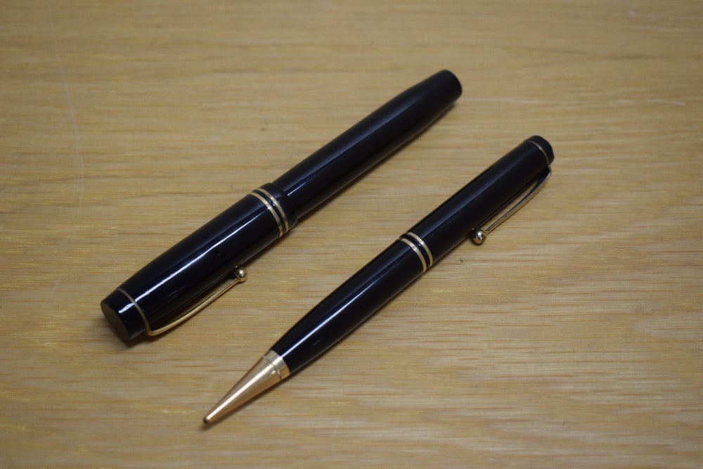 A Parker Duofold Special Short button fill fountain pen and propelling pencil in black with two: A Parker Duofold Special Short button fill fountain pen and propelling pencil in black with two bands to the cap having Parker Duofold 18ct Pen Canada nib