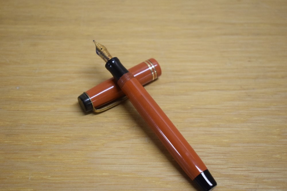 A Parker Duofold Junior button fill fountain pen in orange with two gold bands to the cap having (1 of 3)