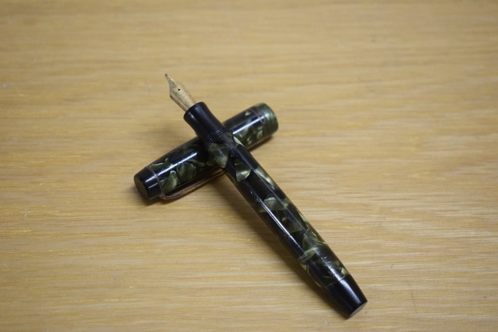A Parker Duofold Deluxe Special Streamline button fill fountain pen in green and black marble with: A Parker Duofold Deluxe Special Streamline button fill fountain pen in green and black marble with two cap bands having Parker Duofold 14k Pen N nib.