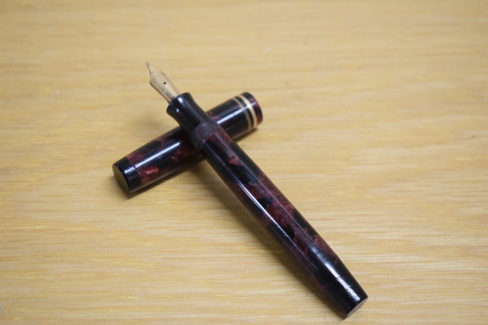 A Parker Duofold Special Streamlined Short button fill fountain pen in rose and black with two cap: A Parker Duofold Special Streamlined Short button fill fountain pen in rose and black with two cap bands having Parker Duofold Pen Canada D nib. No Clip