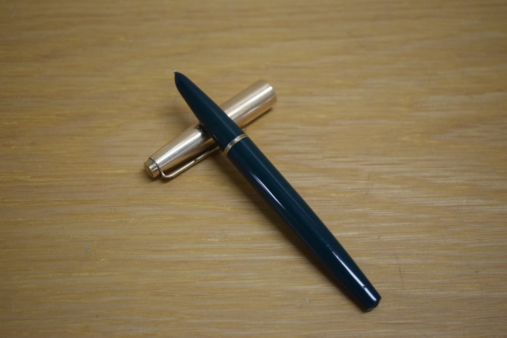 A Parker 51 MKII Demi aerometric fill fountain pen in forest green rolled gold cap. Slight chew to: A Parker 51 MKII Demi aerometric fill fountain pen in forest green rolled gold cap. Slight chew to tassie