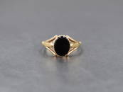 A 9ct gold signet ring having an oval onyx panel in a collared mount to split shoulders, size Q &