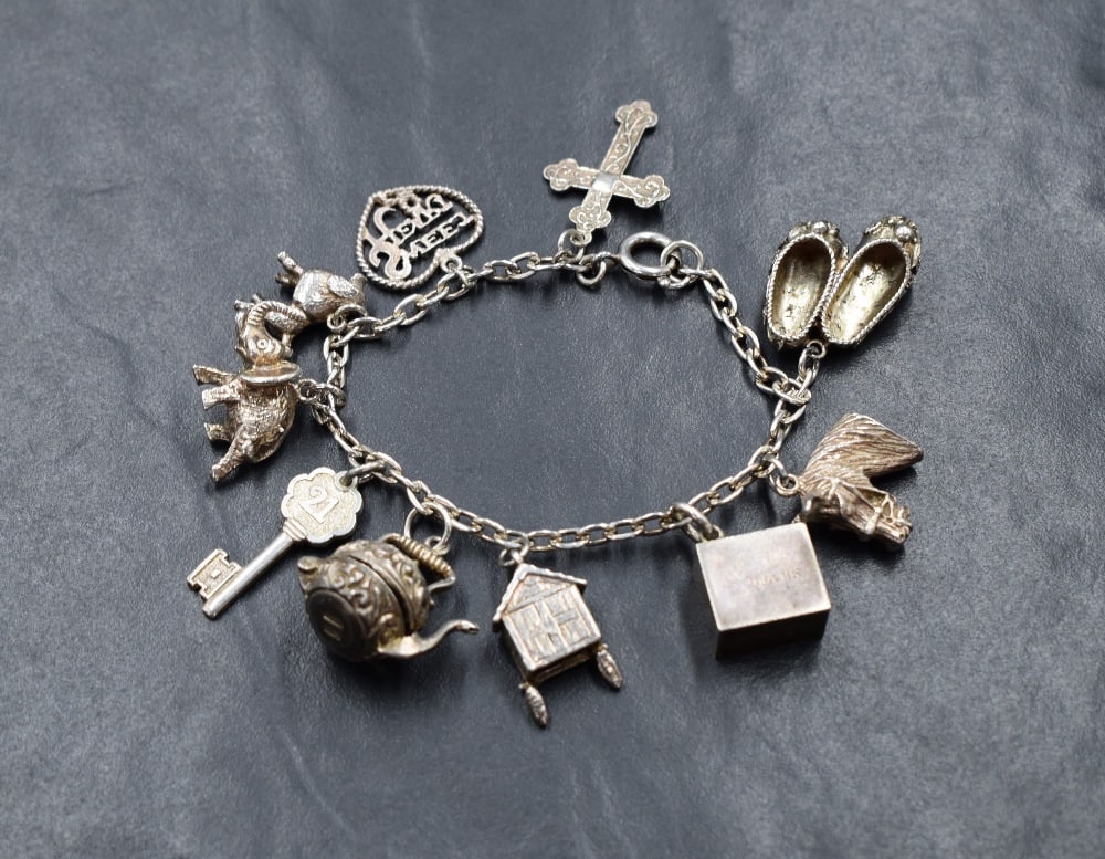 A silver belcher link charm bracelet, having ten silver and white metal charms, including a cross, a (1 of 1)