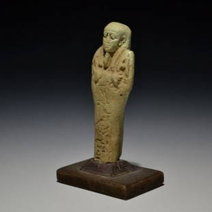 AN EGYPTIAN USHEBTI WITH HIEROGLYPHIC TEXT: AN EGYPTIAN USHEBTI WITH HIEROGLYPHIC TEXTEgyptian / Late Period, ca. 664-332 B.C. / Faience / H = 8,6 cm (3 25/64 in)Ushebti in light green faience with engraved hieroglyphic inscription. Mounted on