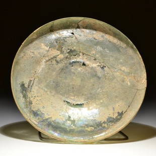 A VERY BIG ROMAN GLASS PLATE: A VERY BIG ROMAN GLASS PLATE Roman / 1st - 2nd cent. A.D. / Glass / D = 23 cm (9 1/16 in)A rvery big roman glass plate with ring-shaped foot formed by a glass bubble and with off set rim. The surface