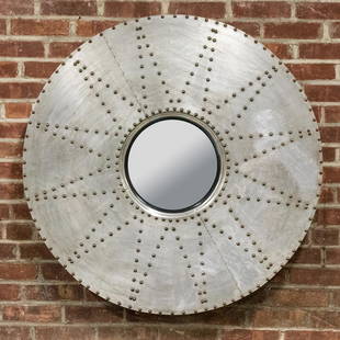 Industrial Style Round Metal Starburst Mirror: Industrial style round mirror in metal with starburst design outlined by metal rivets framing the central mirror. The metal rivets are also used as accents to line the outermost circumference of the m