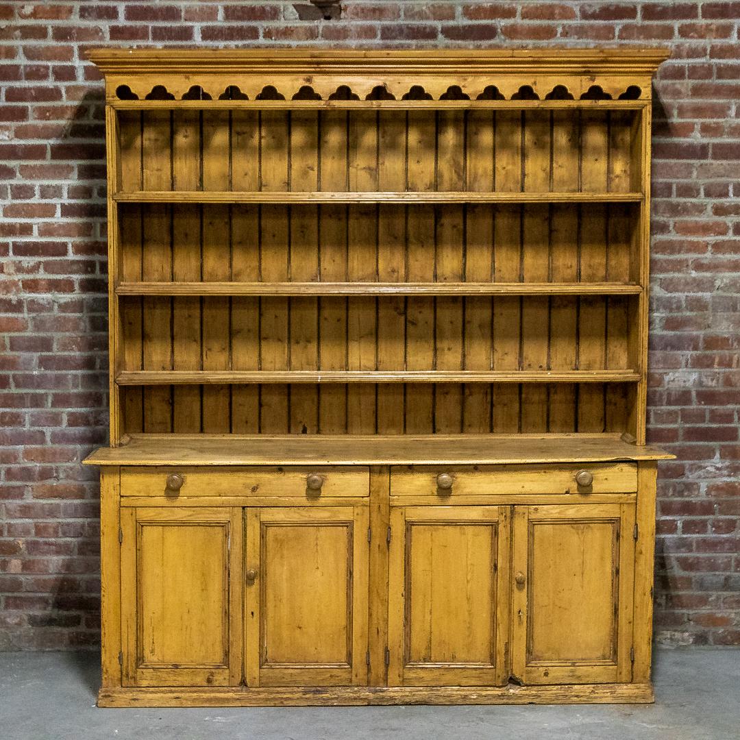 19th Century Pinewood Step Front Cabinet: Circa 19th century pinewood step front cabinet with molded upper cornice and trefoil trim. The piece also features four horizontal step front shelves over two horizontal drawers and a pair of two-door