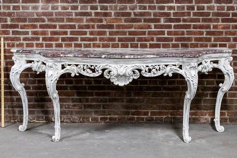 William Kent Style Painted Console Table with Shaped Marble Top: White painted William Kent style carved wood console table with shaped brown and white marble top on cabriole legs. The table features a carved table skirt with pierced, scrolled foliage and a central