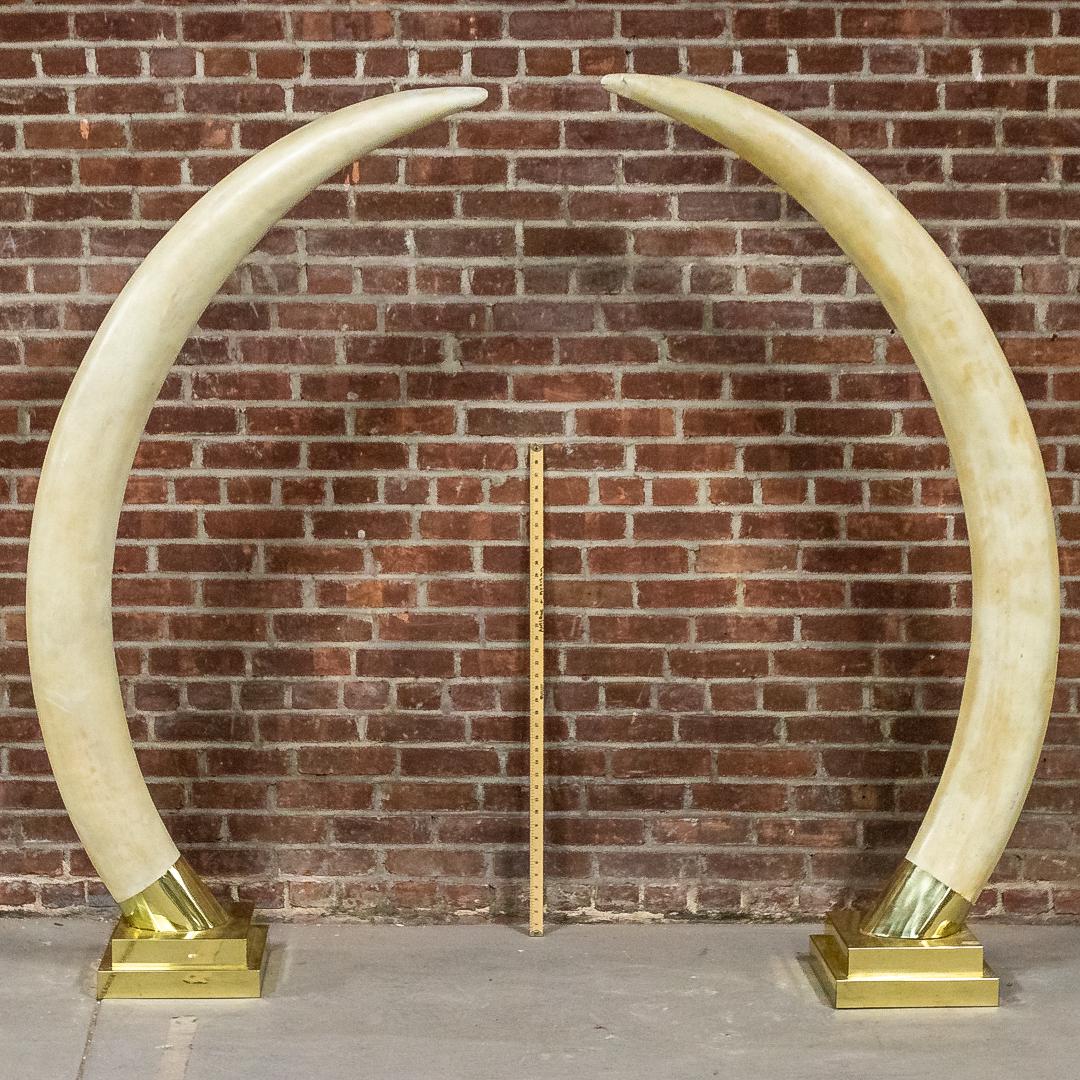 Pair of Life Size Faux Composition Elephant Tusks: Pair of life size faux composition elephant tusks mounted on metal bases. Please note of wear consistent with age including patina, chips, and finish loss to the composition and scratches to the base.