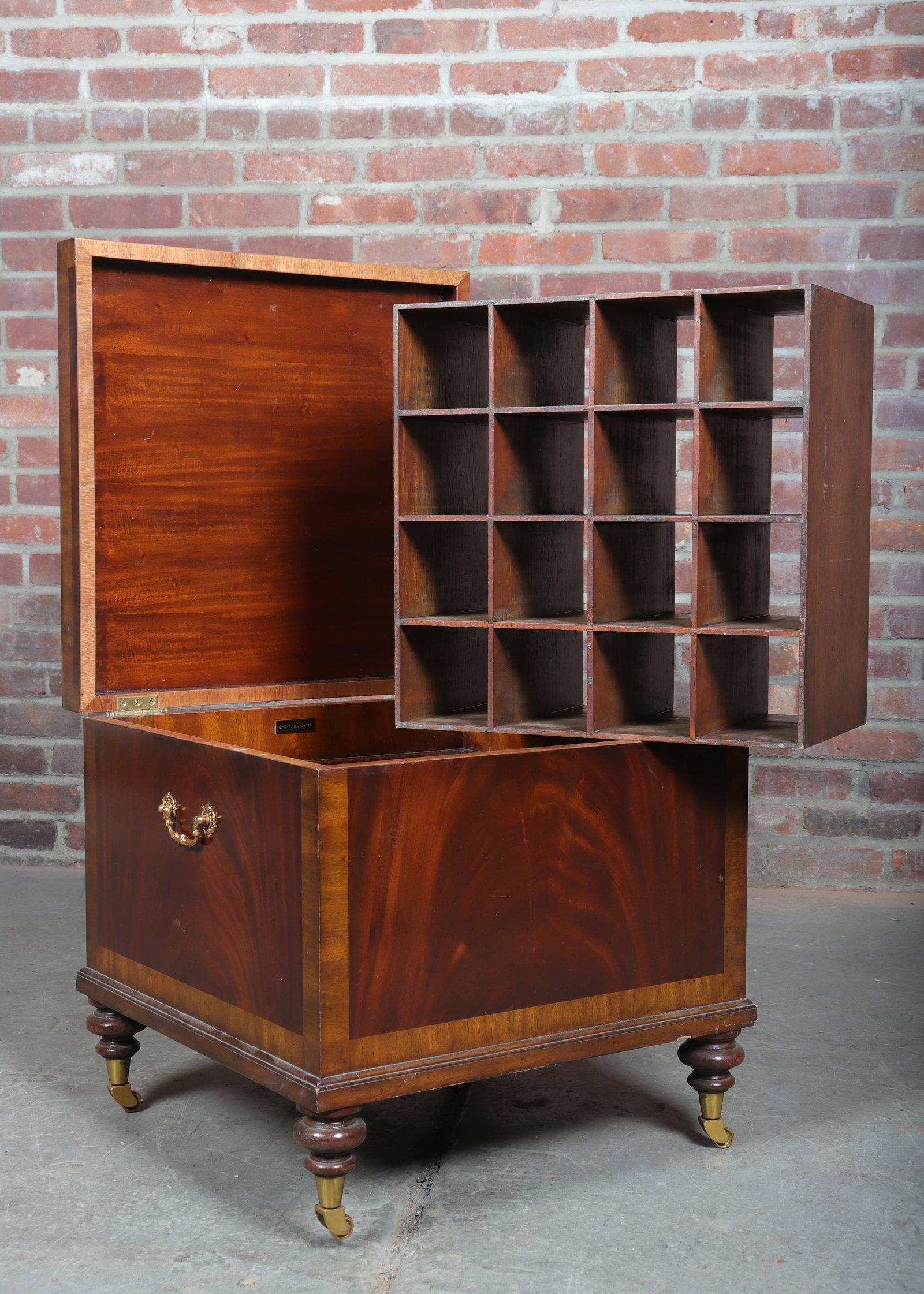Maitland Smith Wine Chest: Square body Maitland Smith sixteen bottle wine chest has a removeable storage bottle spacer. Light tone wood inlay borders surround darker tone single piece siding. Brass handles, stout turned bulbous