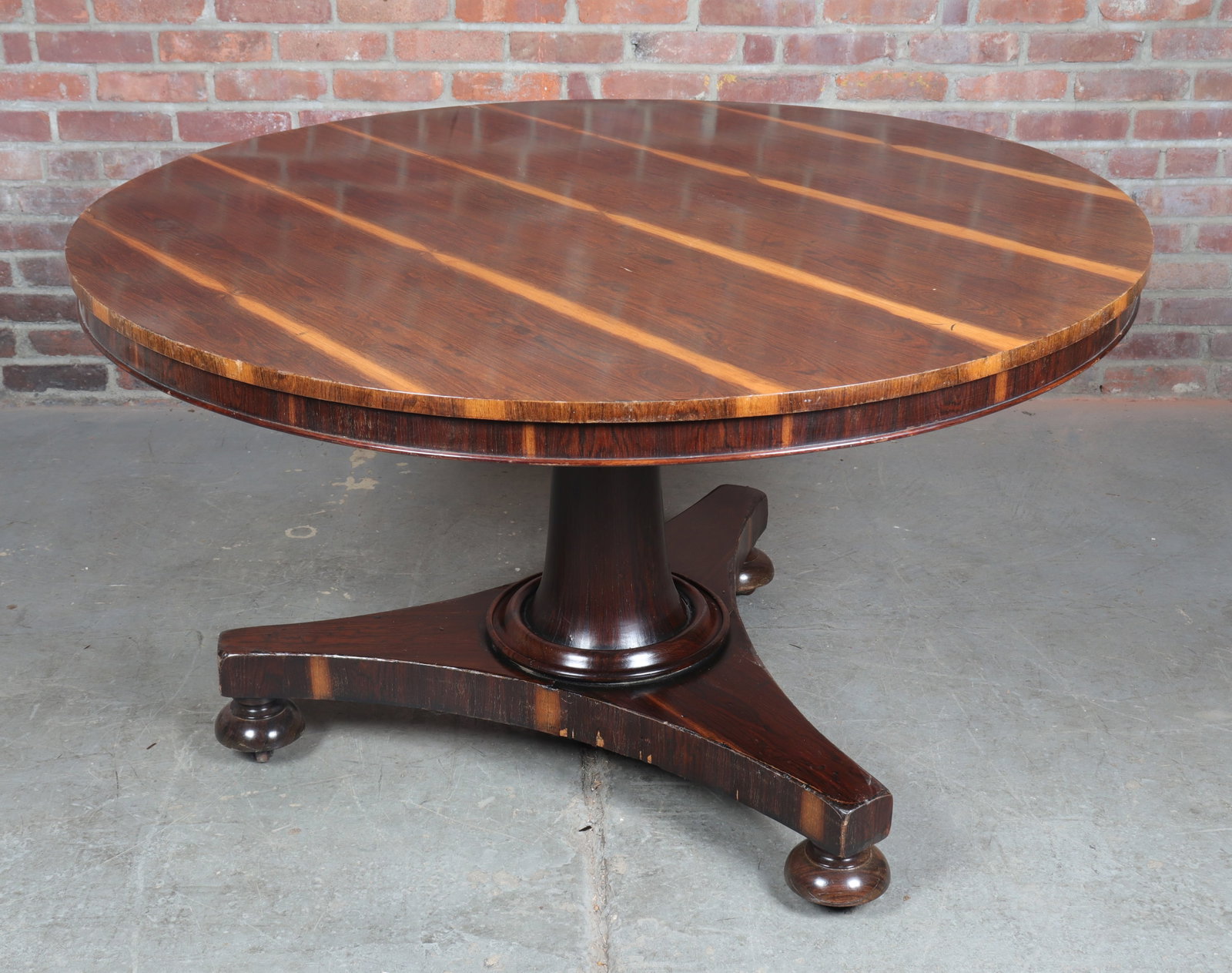 Rosewood Tilt Top Center Table with Tapering Pedestal and Bun Feet: Rosewood tilt top center table with a tapering pedestal, tri-directional base, beveled lower edge on bun feet.