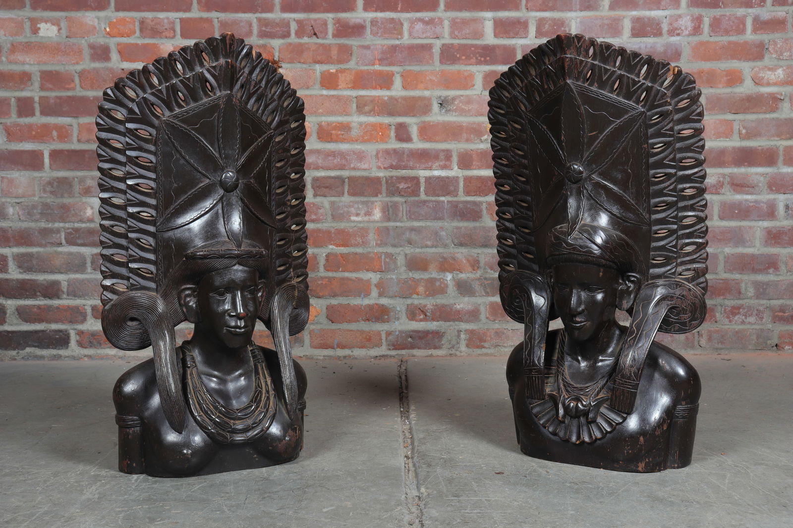 Pair of Male and Female Ebonized Chieftain Tribal Figures: Pair of male and female ebonized tribal figures with chieftain head garb. Pierced sections throughout with fully carved detail from the mid-chest up front and back. Likely African, possibly Balinese.
