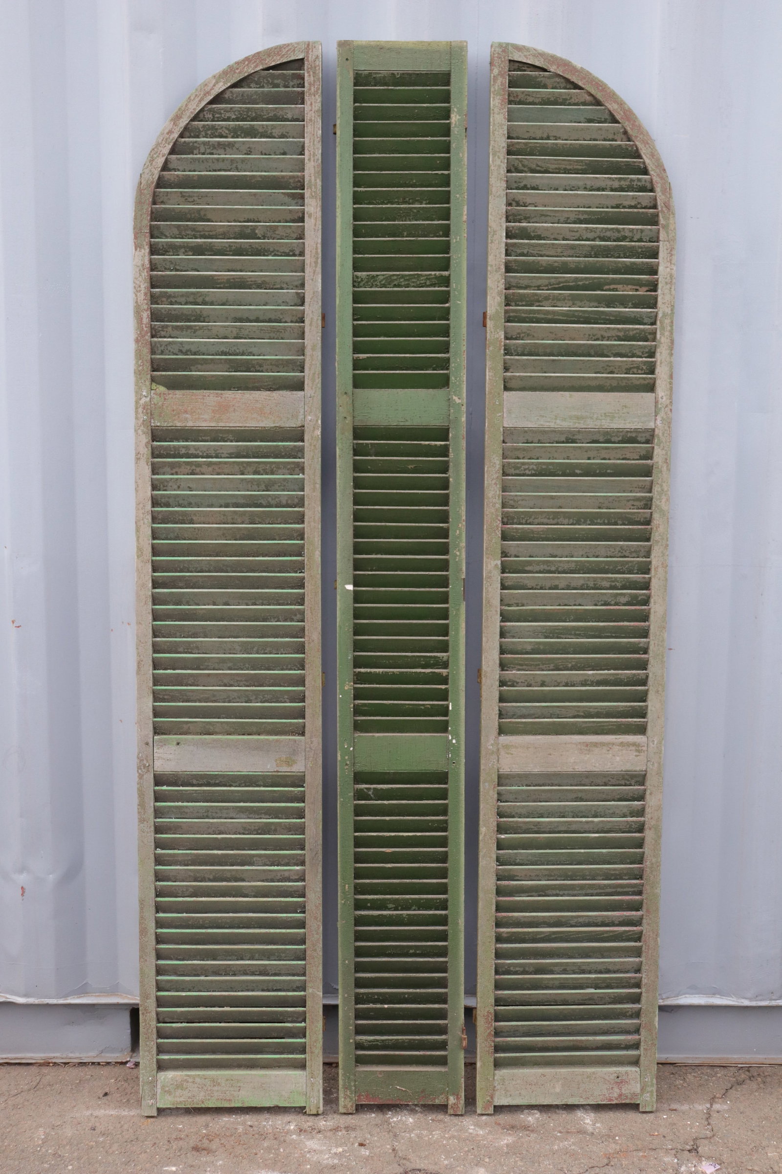Set of Three Decorative Shutter Remnants: A set of three green decorative shutter remnants with craquelure. Two with half domed tops measure 15.5" wide while the single middle piece measures 10.5" wide. All three measure 43" wide.
