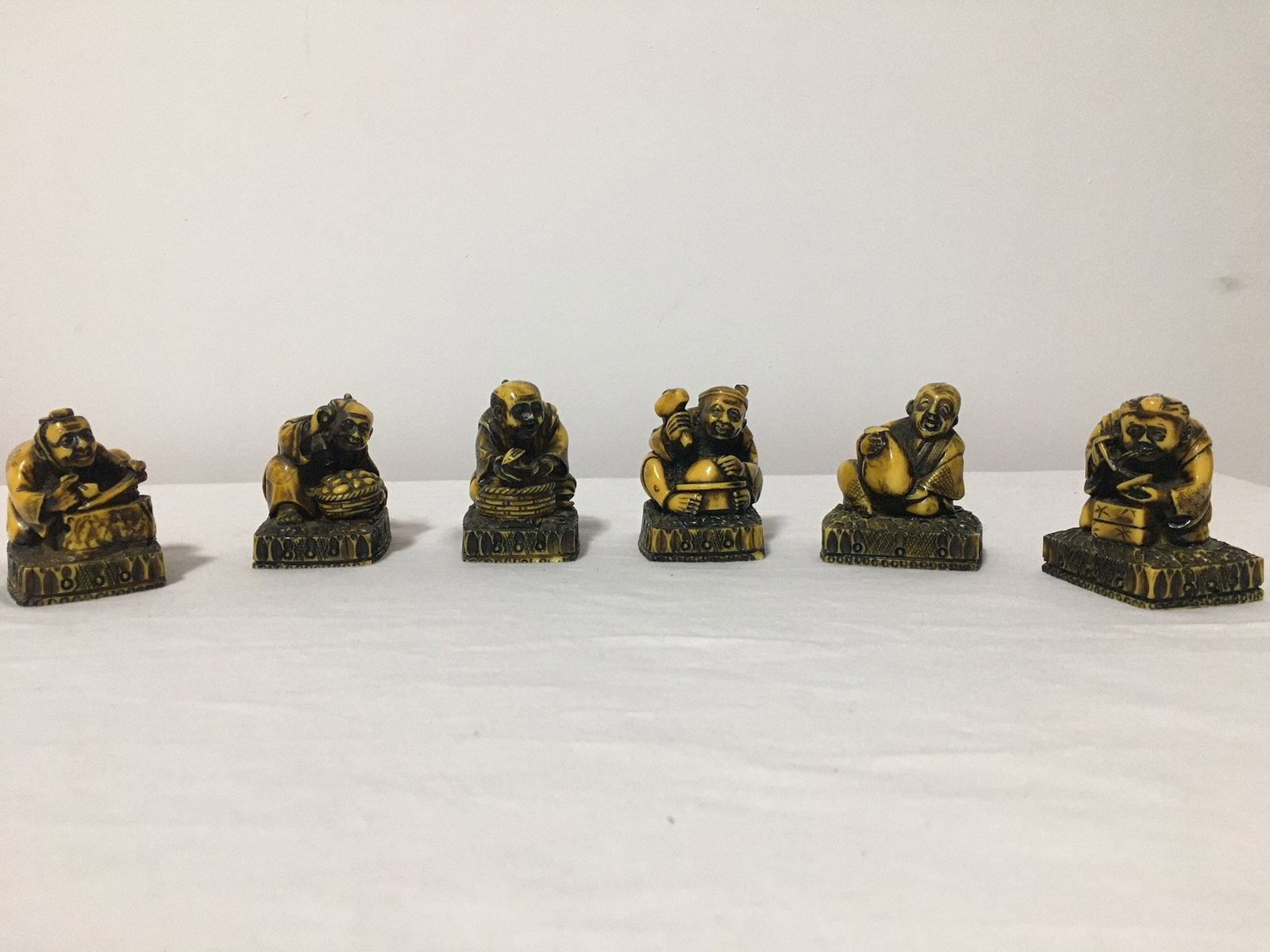 SIX JAPANESE CARVED BONE NETSUKES: Description: Composed of six individually finely carved bone netsukesEach one represents a different character or group of characters, they could be six vendors or street workers in full activityEach 