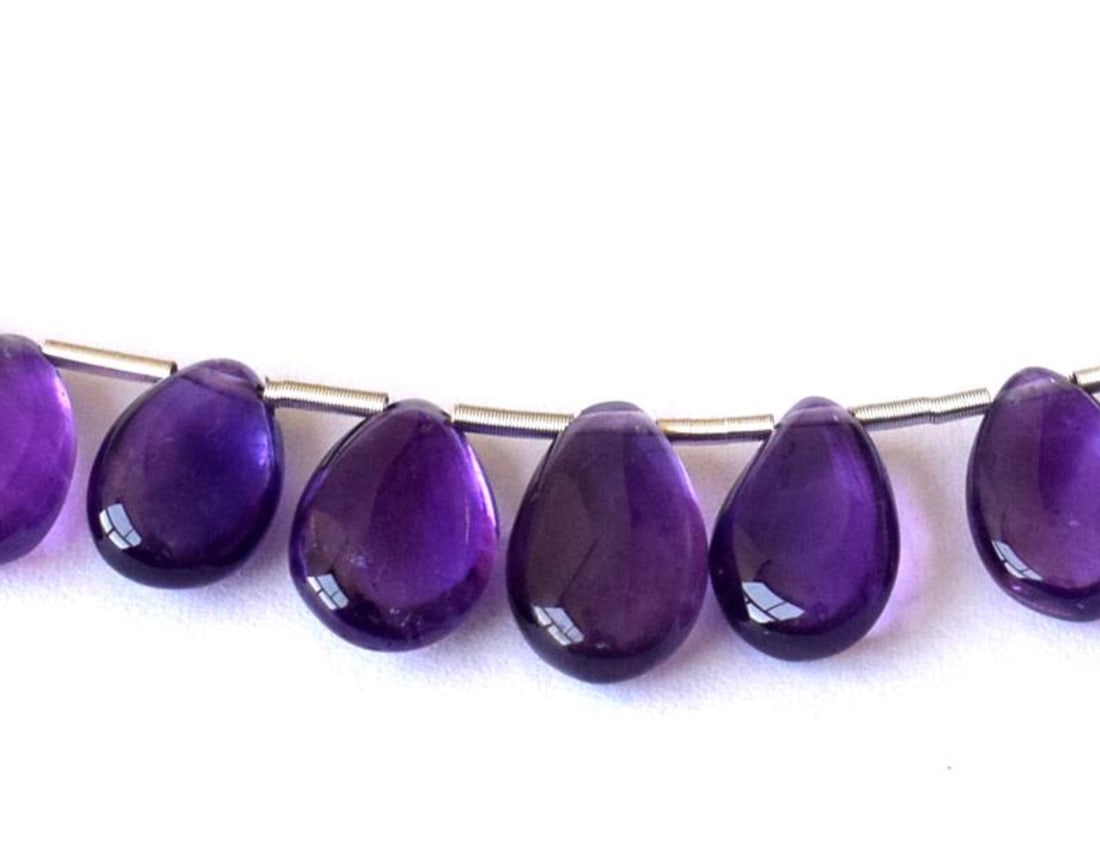 NATURAL AMETHYST BEADS PEAR 6.5X10 - 7X11.5 MM 9 PCS: These are natural, earth mined and hand crafted with precision. Stone: Amethyst, Stone Shape: Pear, Stone Size: 6.5x10 - 7x11.5mm, Width: 3.5 - 4 mm, Weight: approx. 21 carats. The photographs are enl