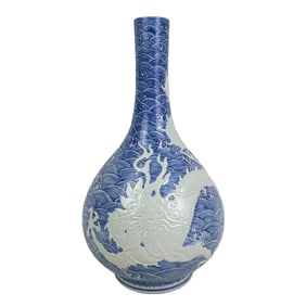 Blue and white porcelain vase with carved dragon and sea wave design.