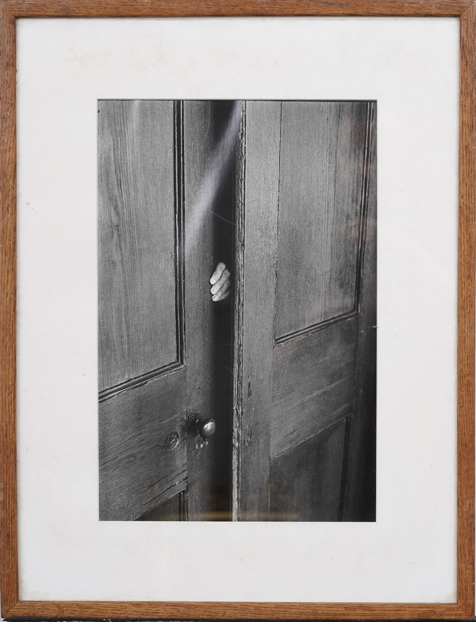 Elliott Erwitt (1928-2023) "Hand in Doorway" – Florida, from "Portfolio of 15 Photographs": Vintage American photograph. Measuring: 22.75 by 17.5 inches overall, and 15.5 by 10.25 painting alone. Please see all images for condition. Size is measured and written on the back of the painting or