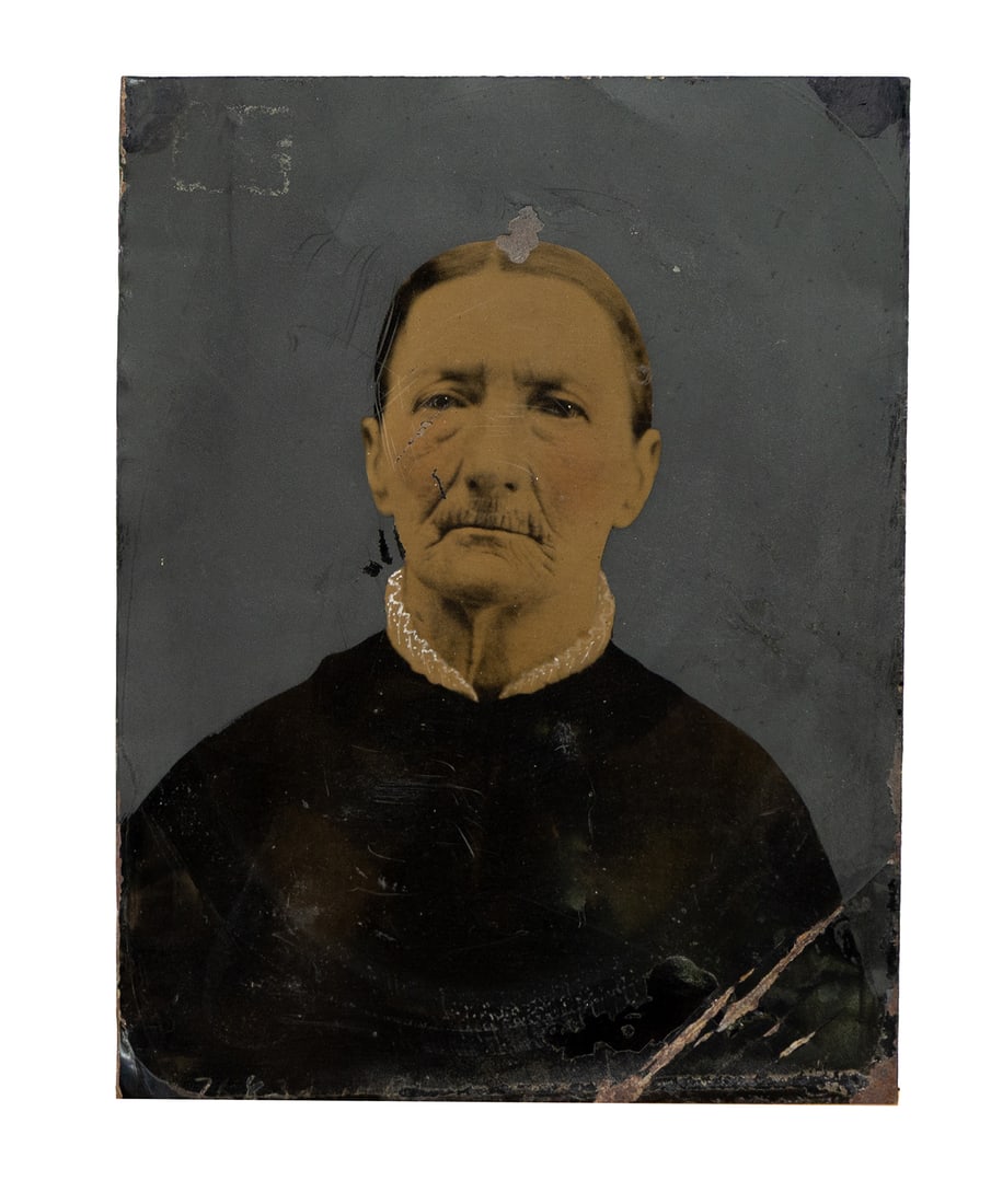 Antique Hand-Tinted Tintype Portrait of an Elderly Woman in Dark Dress: This antique tintype photograph features an elderly woman dressed in a dark garment with a delicate white lace collar. The portrait has been partially hand-tinted, giving her skin a warm sepia tone th