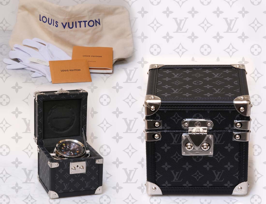 A Louis Vuitton TRUNK TABLE CLOCK: A French Louis Vuitton TRUNK TABLE CLOCK. Clock Details: Stainless steel and mineral glass sphere, Diameter: 3.1", Concave sunray dial in brushed anthracite with Louis Vuitton flags Bicolor flange wit