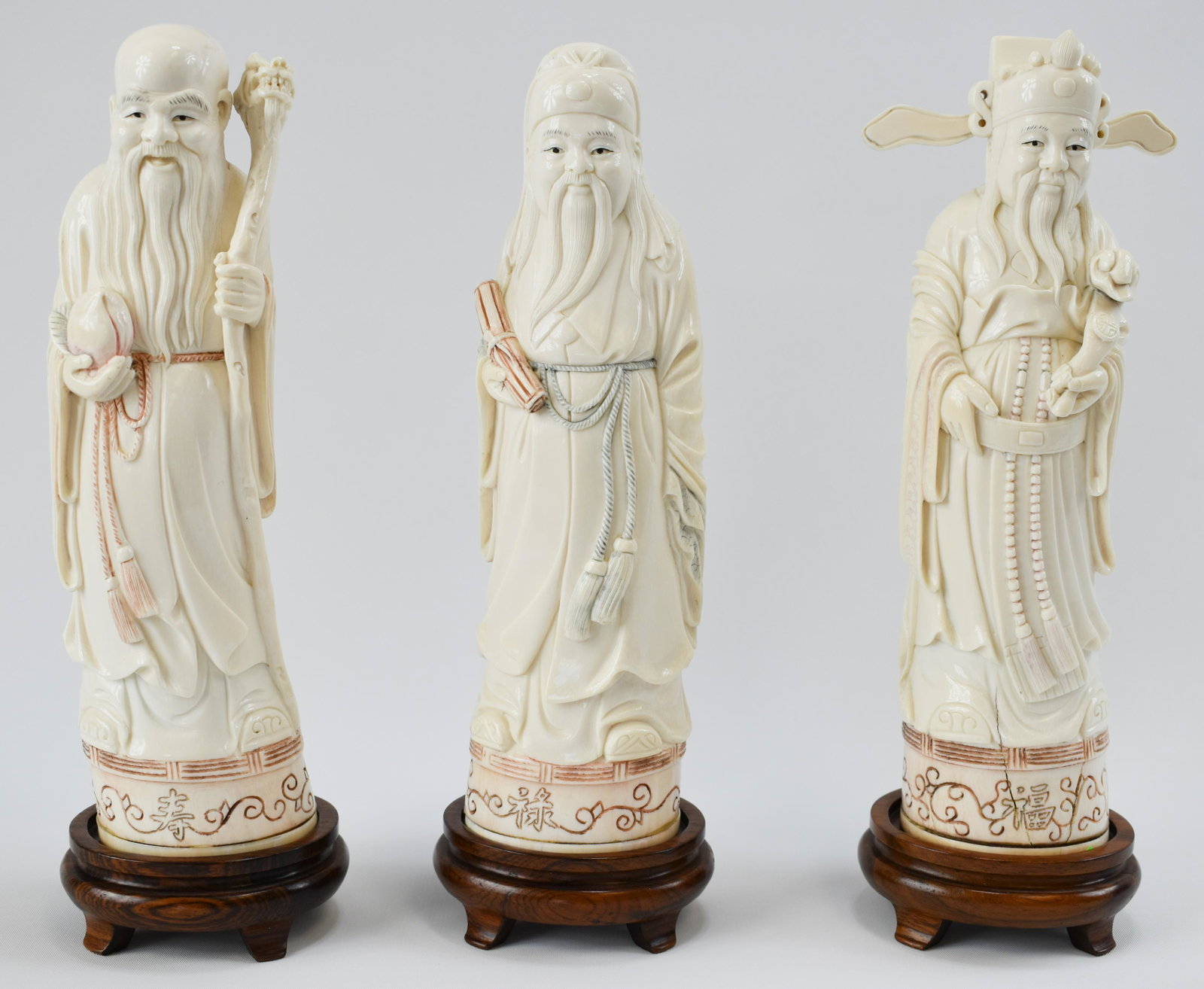 Group of Three Ivory Carvings of "The Three Star Gods": Chinese, First Half 20th Century Each figure standing, holding their typical attribute, the smiling faces, robes, and hats carved with good detail, wood stands. Height: 9" Condition: very good